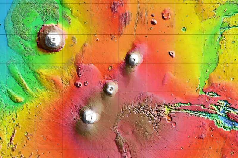 Arsia Mons - самый южный из трех вулканов, которые составляют Tharsis Montes, показанный в центре этой укороченной топографической карты Марса. Olympus Mons, крупнейший вулкан солнечной системы, находится в верхнем левом. Западный конец Valles Marineris начинает разрезать свою широкую полосу через планету в правом нижнем углу. Кредит: НАСА/JPL-CALTECH Orbiter NASA Mars захватывает вулкан, заглядывая над утренними облачными вершинами